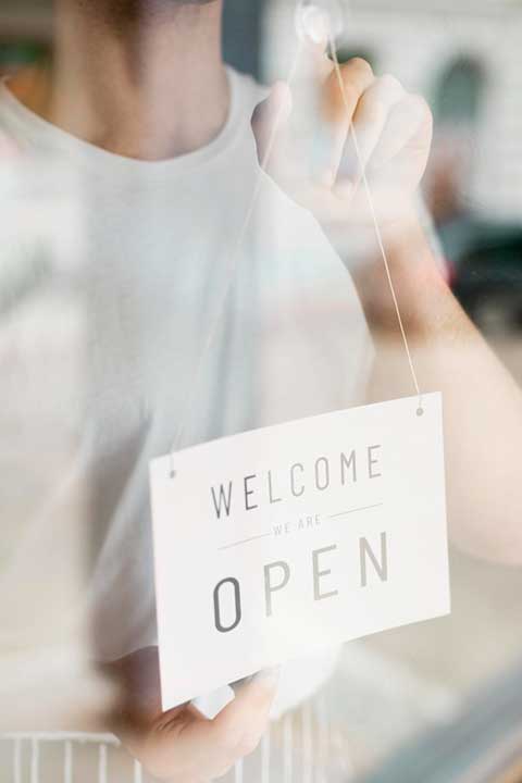 man-putting-up-open-sign-coffee-shop-window